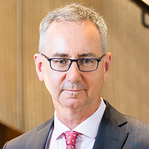 John Lonsdale, professional headshot in office setting with blurred background and neutral tones